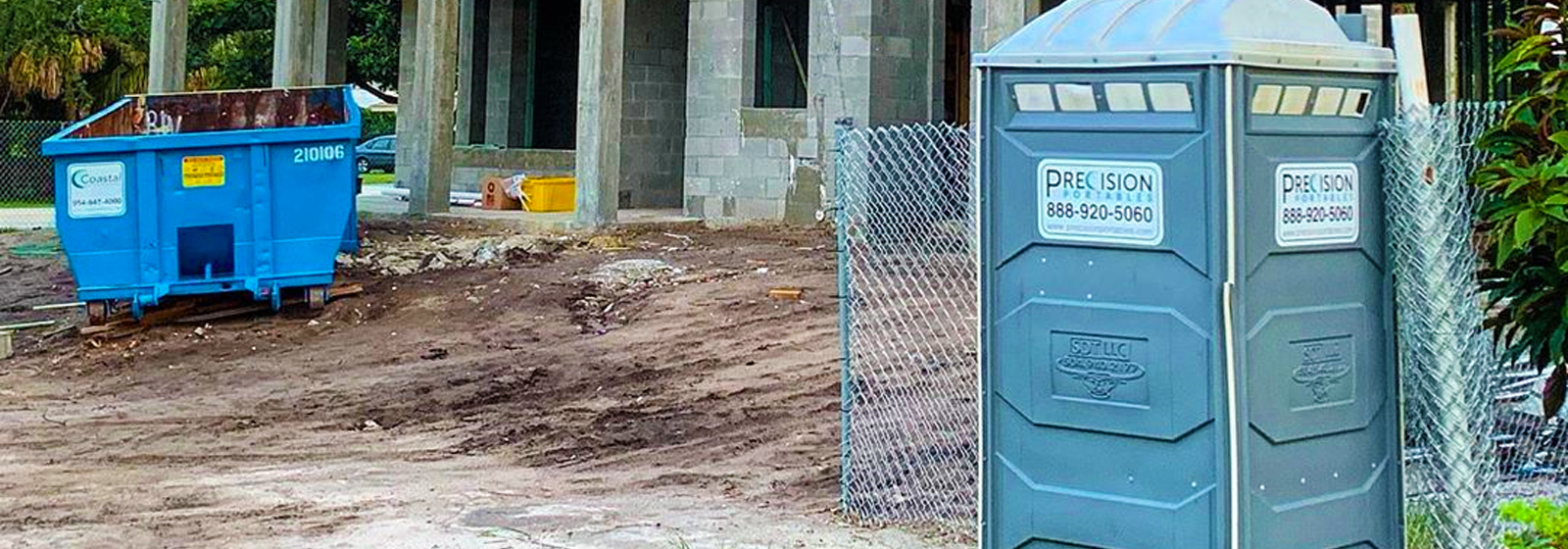 Portable Restroom by Precision Portables shown in front of a home under construction with Coastal Waste Roll Off dumpster in the background